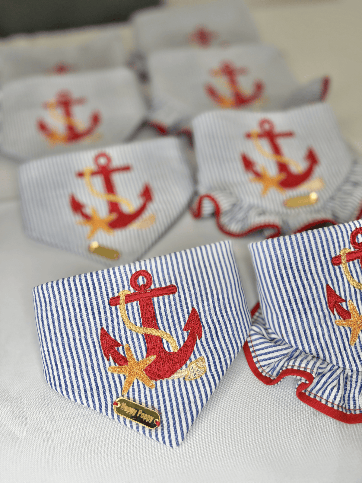 Bandanas para perro Beach Anchor de Happy Puppy Bandanas en rayas azul marino y blanco con ancla bordada en rojo y volante rojo, vista de grupo