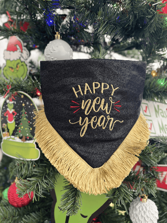 Bandana para perro Happy New Year de Happy Puppy Bandanas, negra con letras Happy New Year bordadas en dorado y fleco dorado, colgada en un arbol de Navidad