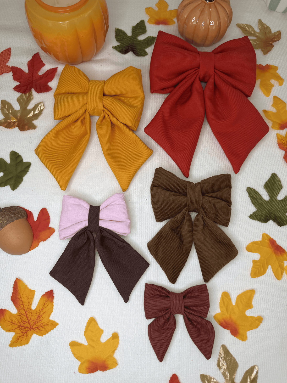 Sailor bows para collar de perro de Happy Puppy Bandanas en tonos de otono mostaza, vino, marron y rosa, vista de grupo sobre hojas y calabazas decorativas